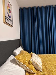 Bedroom with rich blue drapes and gold accent pillows