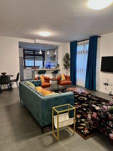 Living room with green velvet sofa, smart TV and dining area