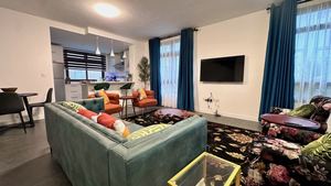 Furnished lounge with smart TV and blue accent drapes