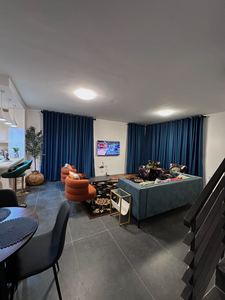 Bright living space with floor-to-ceiling blue drapes and accent seating